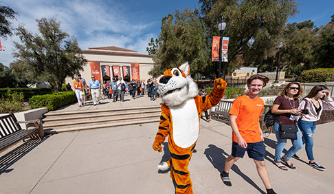 Oswald the Tiger strolls in front of Thorne Hall with students, alumni, and families