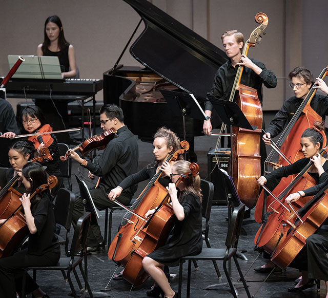 Cellists, violinists, and other musicians playing in the Occidental College Orchestra