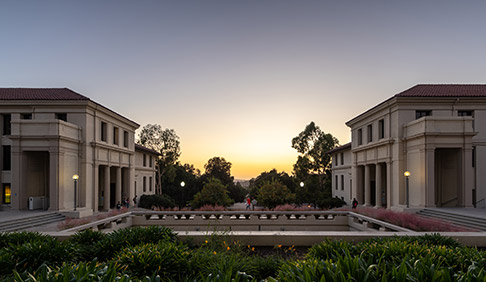 A figure walks across the courtyard in front of AGC with a colorful sunset in the background