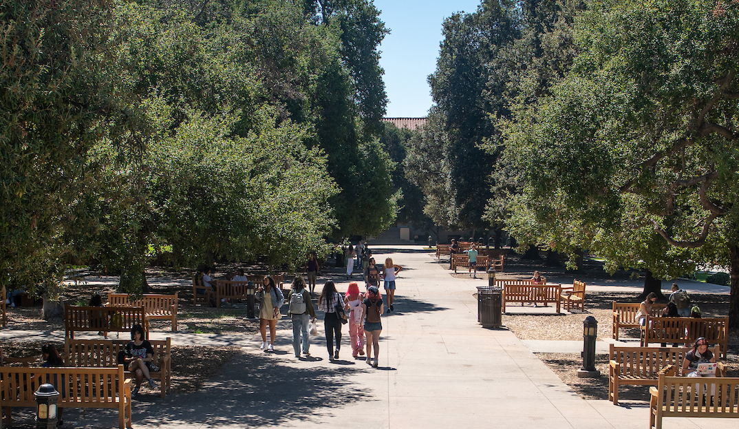 The Academic Quad at mid-day, students are walking down the center pathway