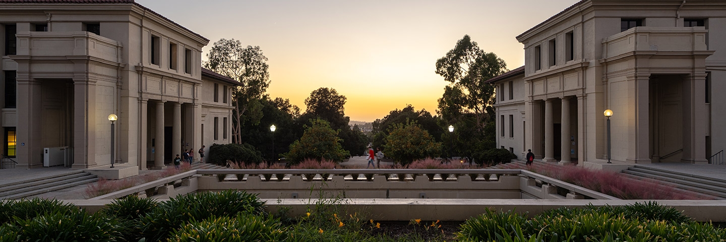 A figure walks across the courtyard in front of AGC with a colorful sunset in the background