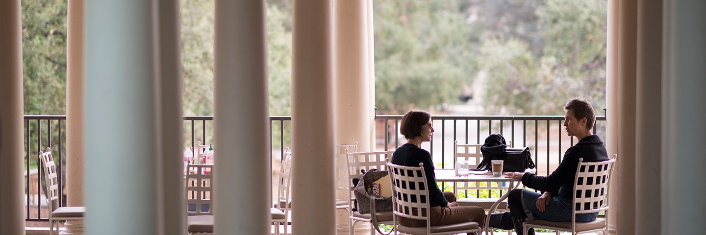 Two figures sit on the Branca patio at JSC framed by columns on either side