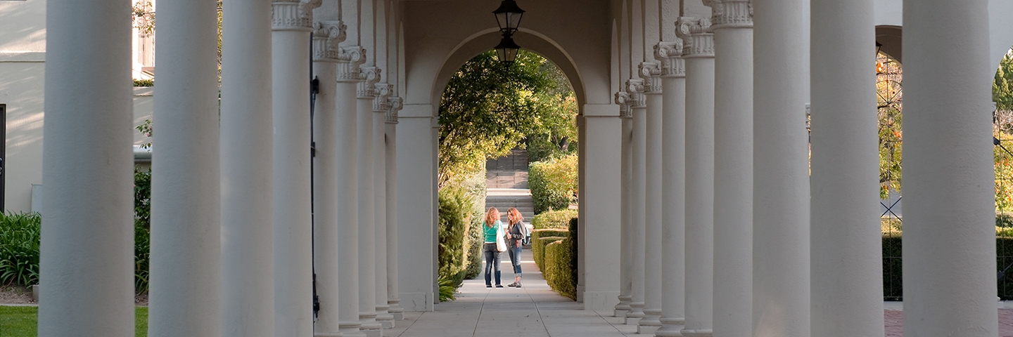 Two people standing under building archway