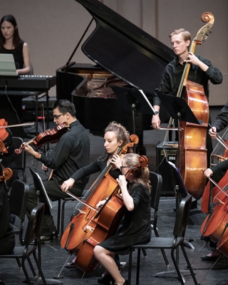 Cellists, violinists, and other musicians playing in the Occidental College Orchestra